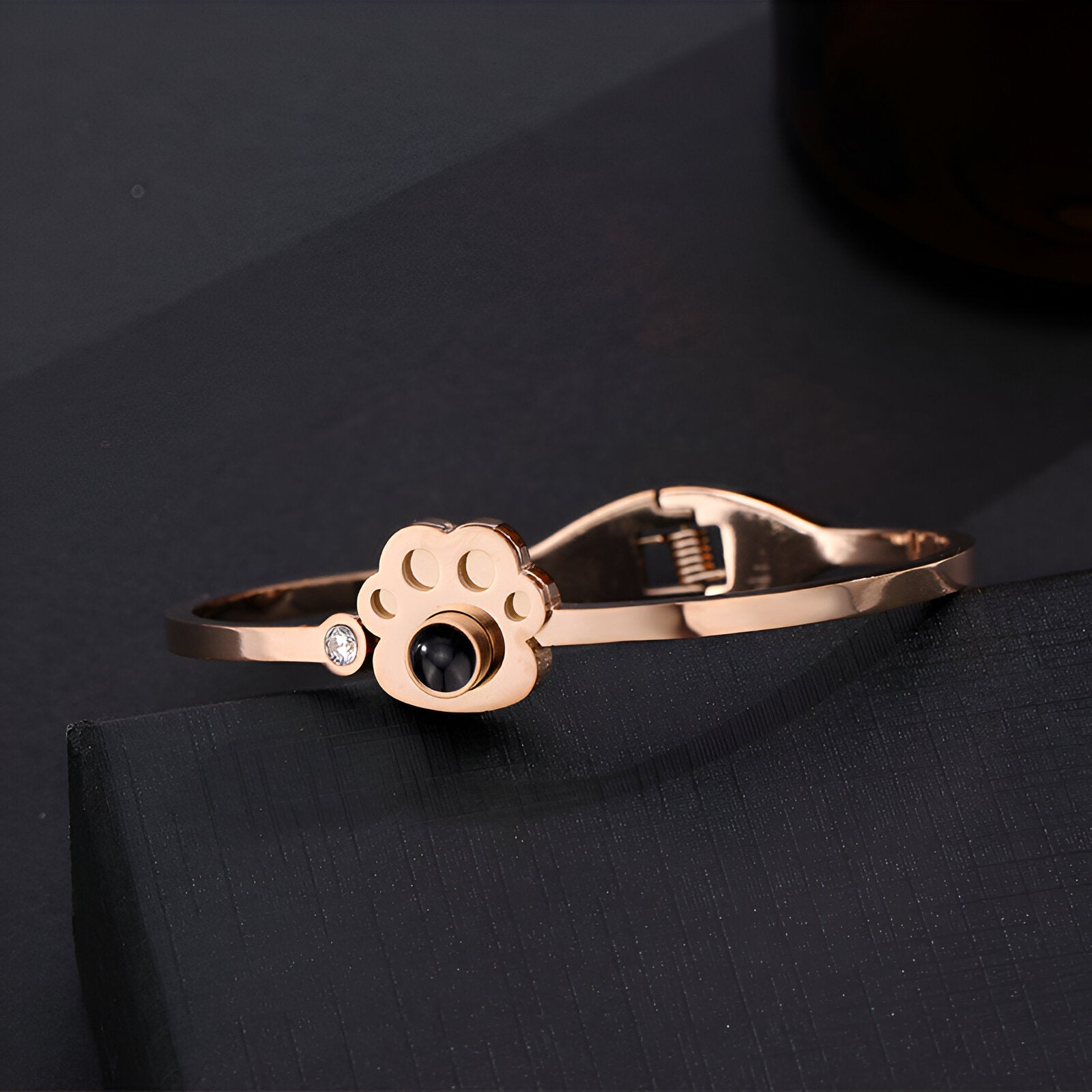 Bracelet en titane or rosé avec patte d'animal gravée et pierre noire brillante.