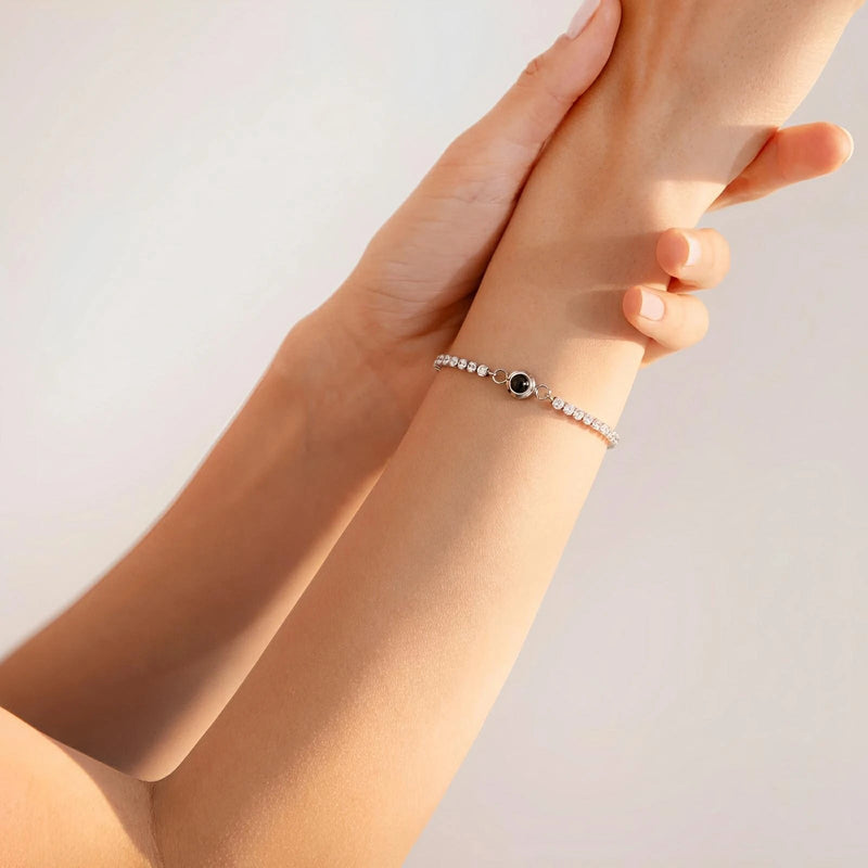 Bracelet titane argenté à chaîne fine avec disque photo personnalisé noir sur poignet féminin.