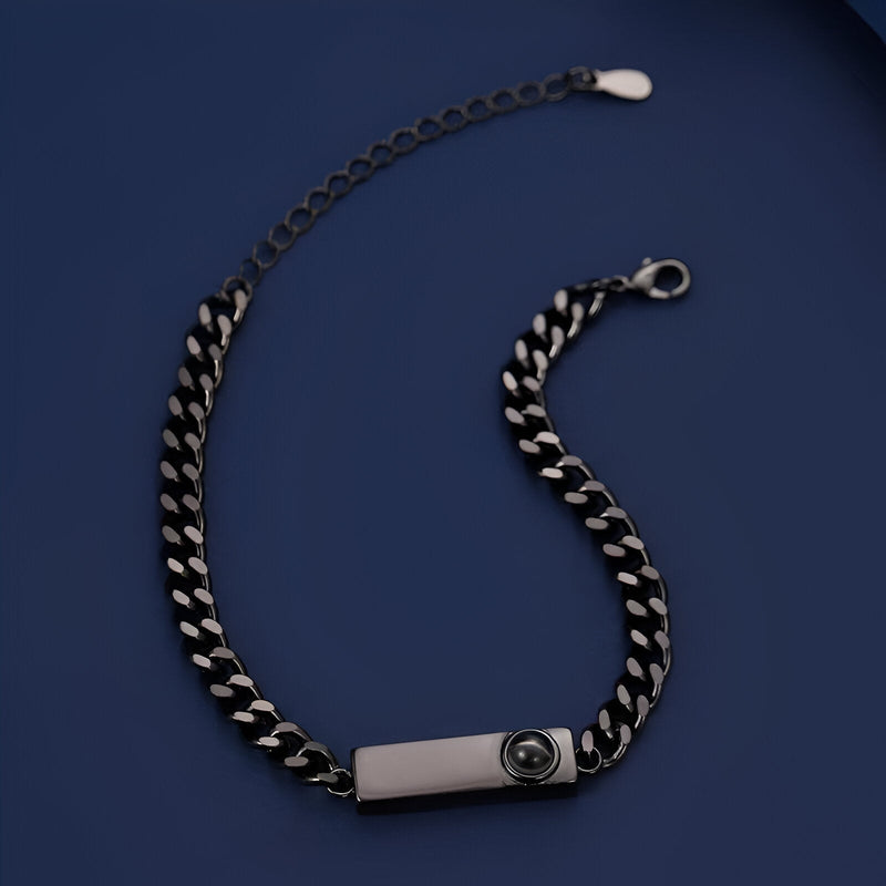 Bracelet gourmette en titane noir avec plaque gravée et chaîne épaisse à maillons larges.