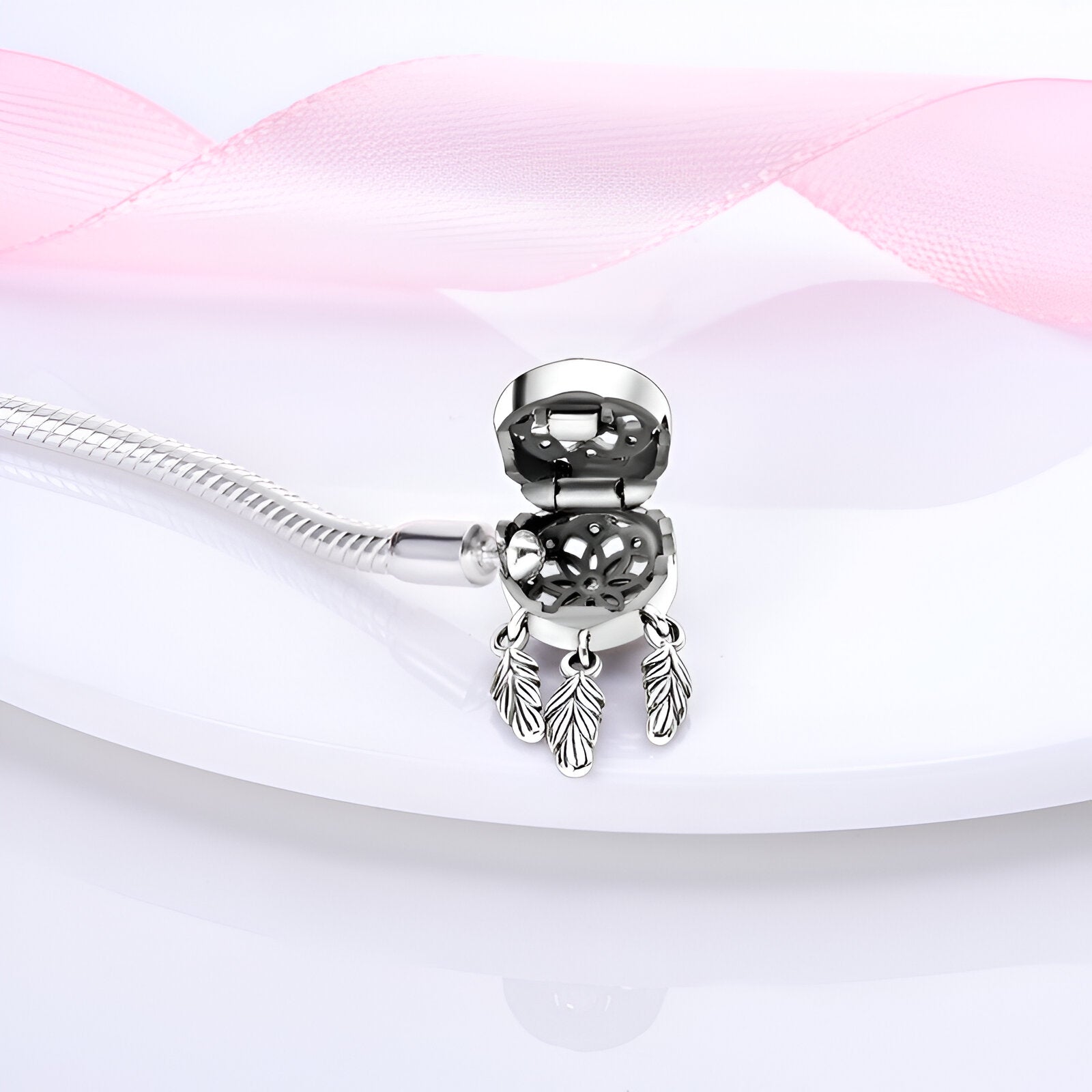 Bracelet argenté fin avec charm attrape-rêves orné de trois plumes délicates.