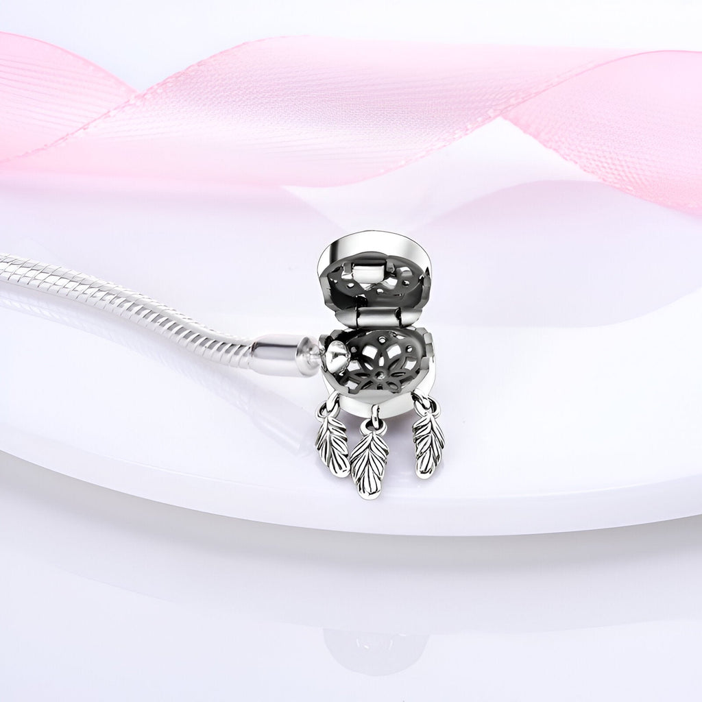 Bracelet argenté fin avec charm attrape-rêves orné de trois plumes délicates.