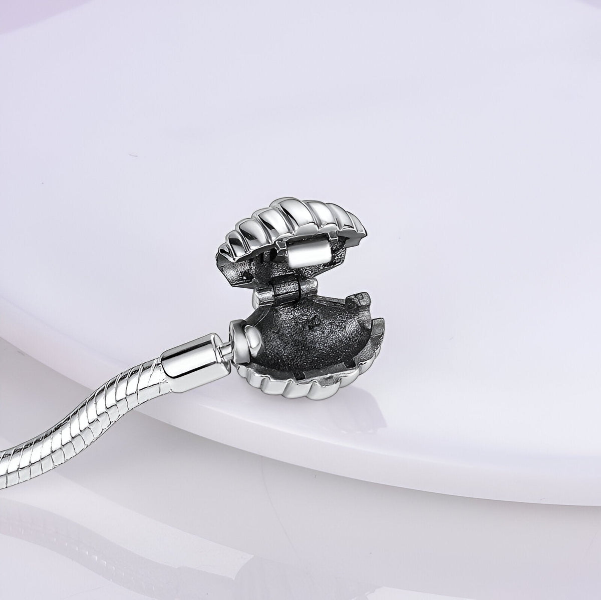 Bracelet argenté pour charm avec fermoir coquillage ouvert montrant intérieur texturé.
