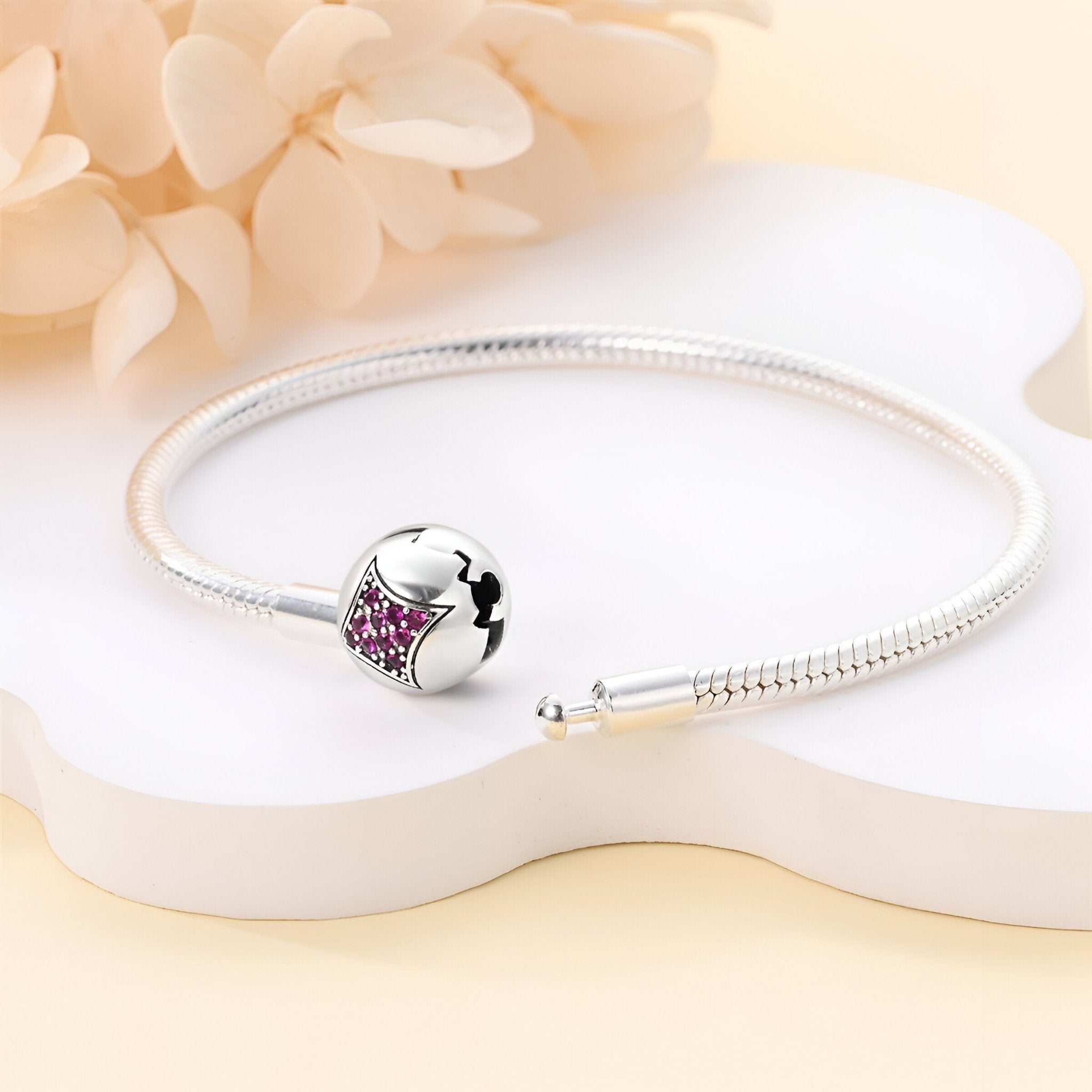 Bracelet en argent fin avec un charm étoile rose orné de cristaux sur fond blanc crème.