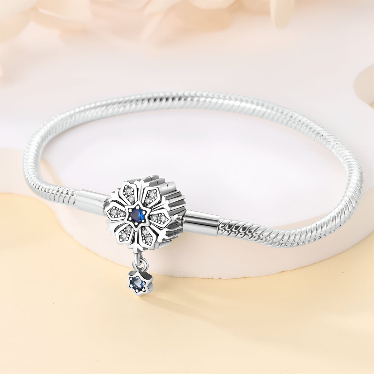 Bracelet argenté serpent avec charm fleur orné d’un saphir bleu et pendentif goutte bleu.