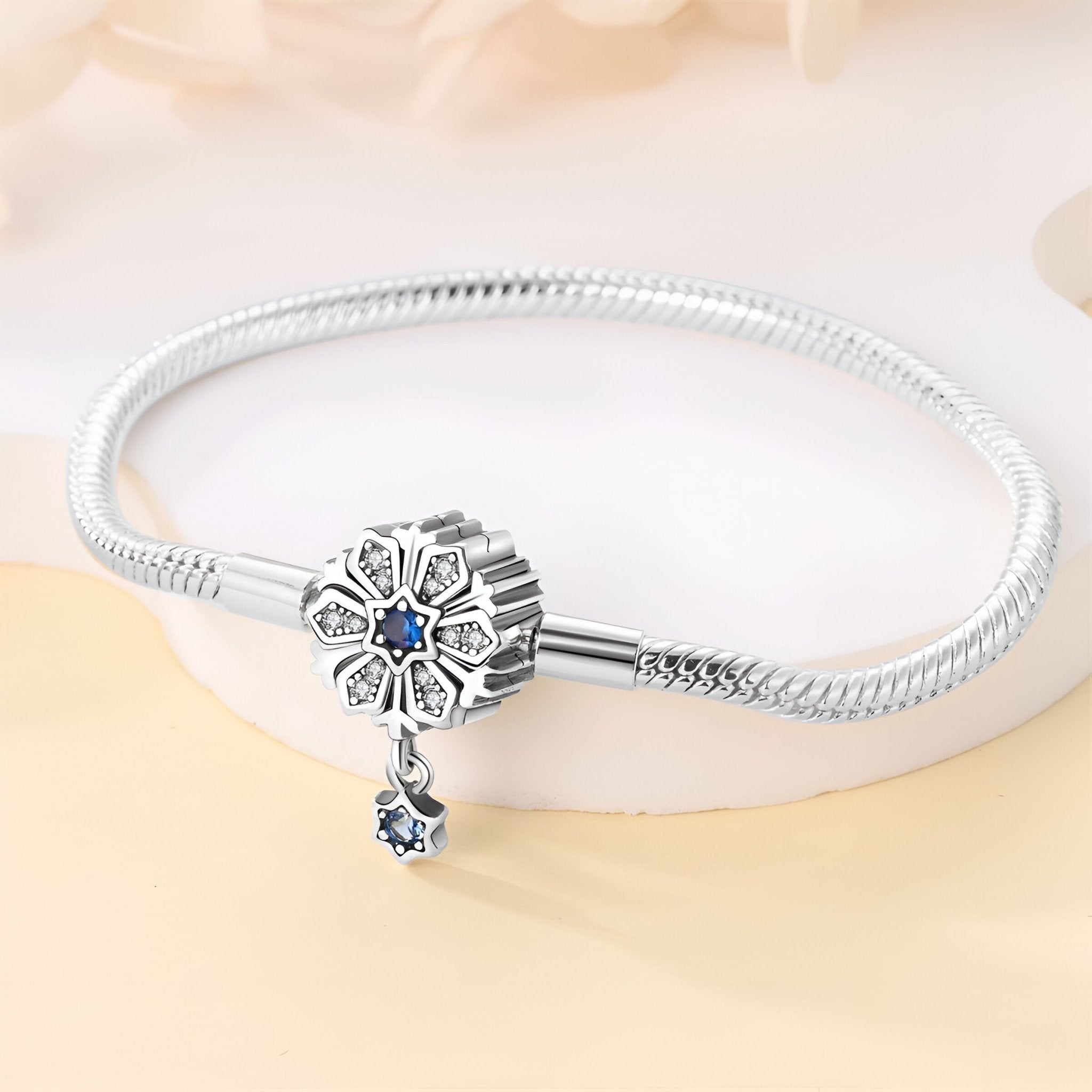Bracelet argenté serpent avec charm fleur orné d’un saphir bleu et pendentif goutte bleu.