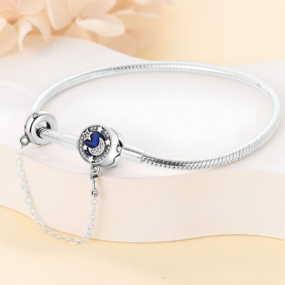 Bracelet argenté fin avec charm rond bleu nuit et étoiles argentées, chaîne de sécurité fine.