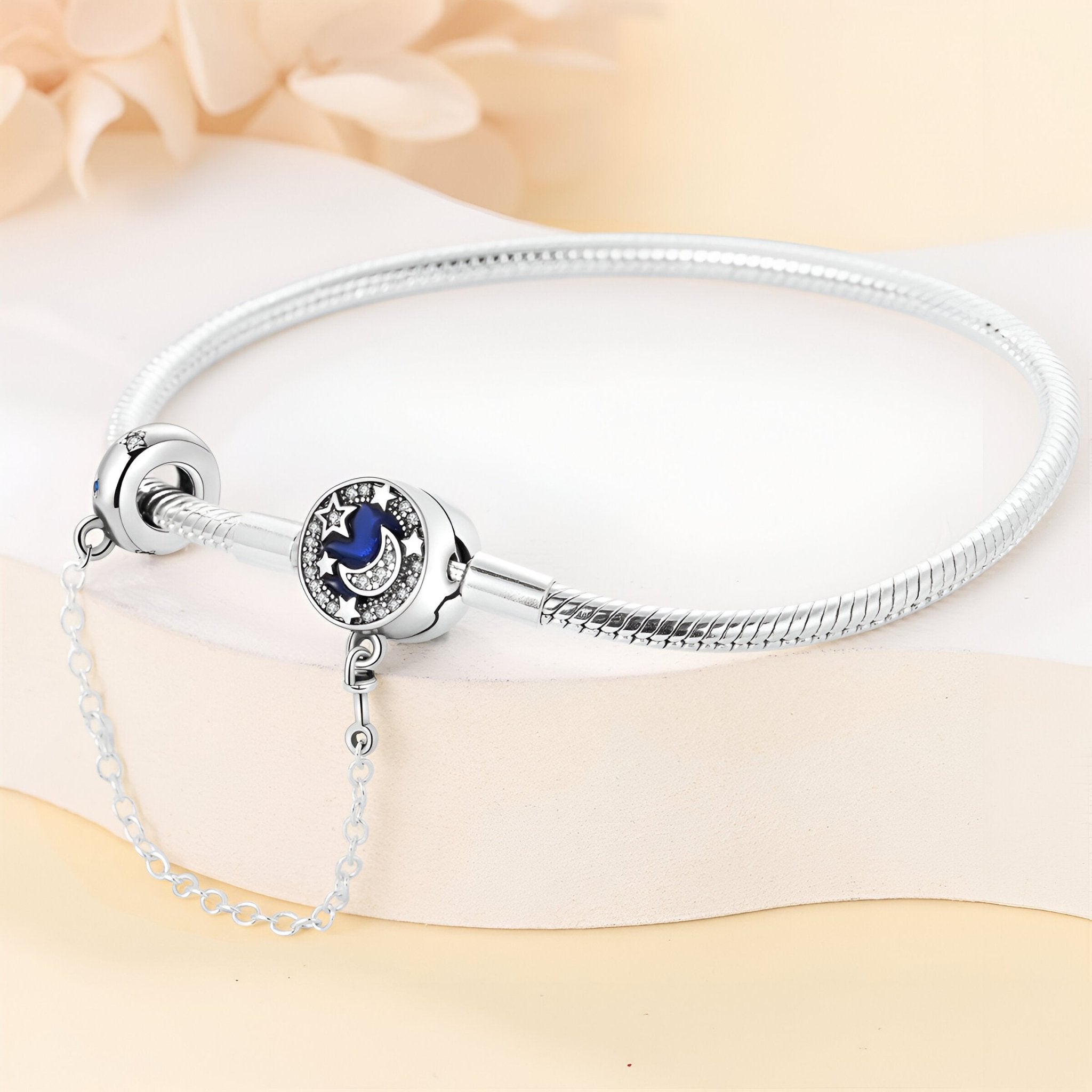 Bracelet argenté fin avec charm rond bleu nuit et étoiles argentées, chaîne de sécurité fine.