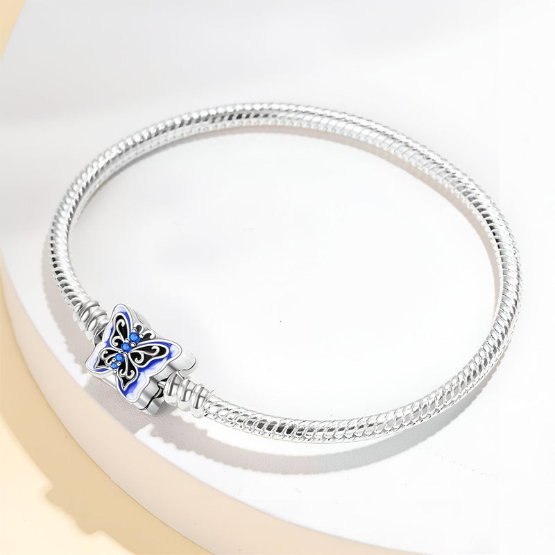 Bracelet argenté souple avec charm papillon bleu détaillé, style élégant et fin.