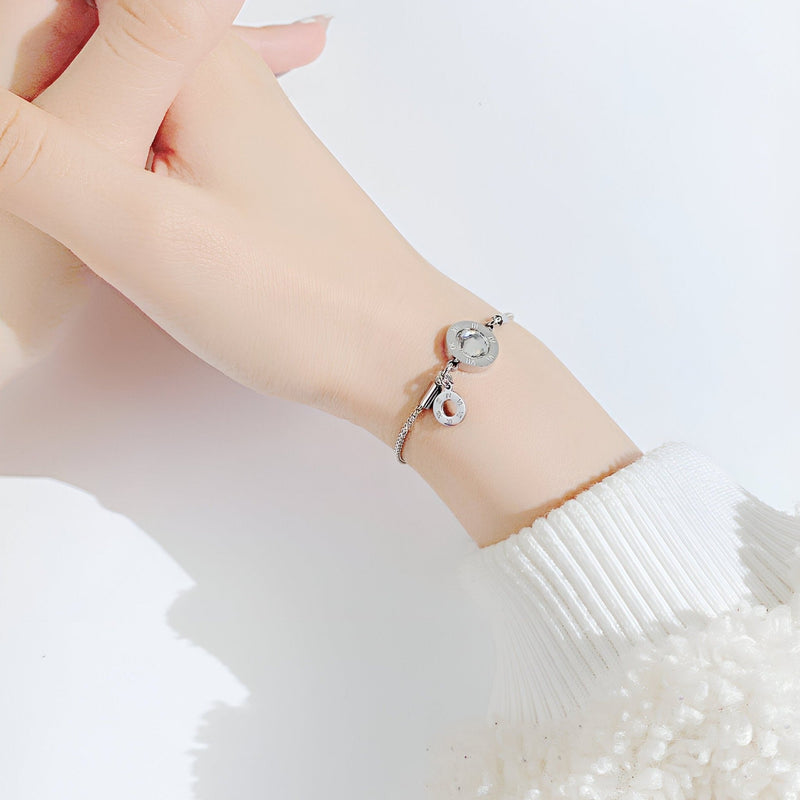 Bracelet femme en acier argenté avec charms chiffres romains en verre, style élégant et délicat.