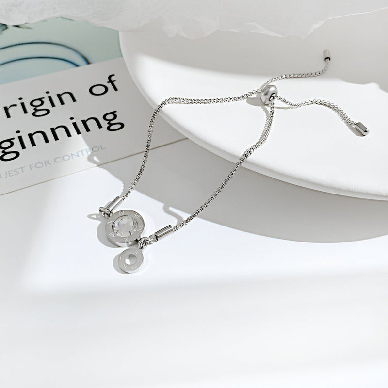 Bracelet femme en acier inoxydable argenté avec charm chiffres romains en verre et fermoir coulissant.