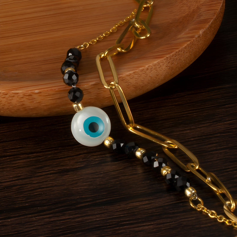 Bracelet femme acier inoxydable or avec perles noires et charm œil du diable bleu et blanc.