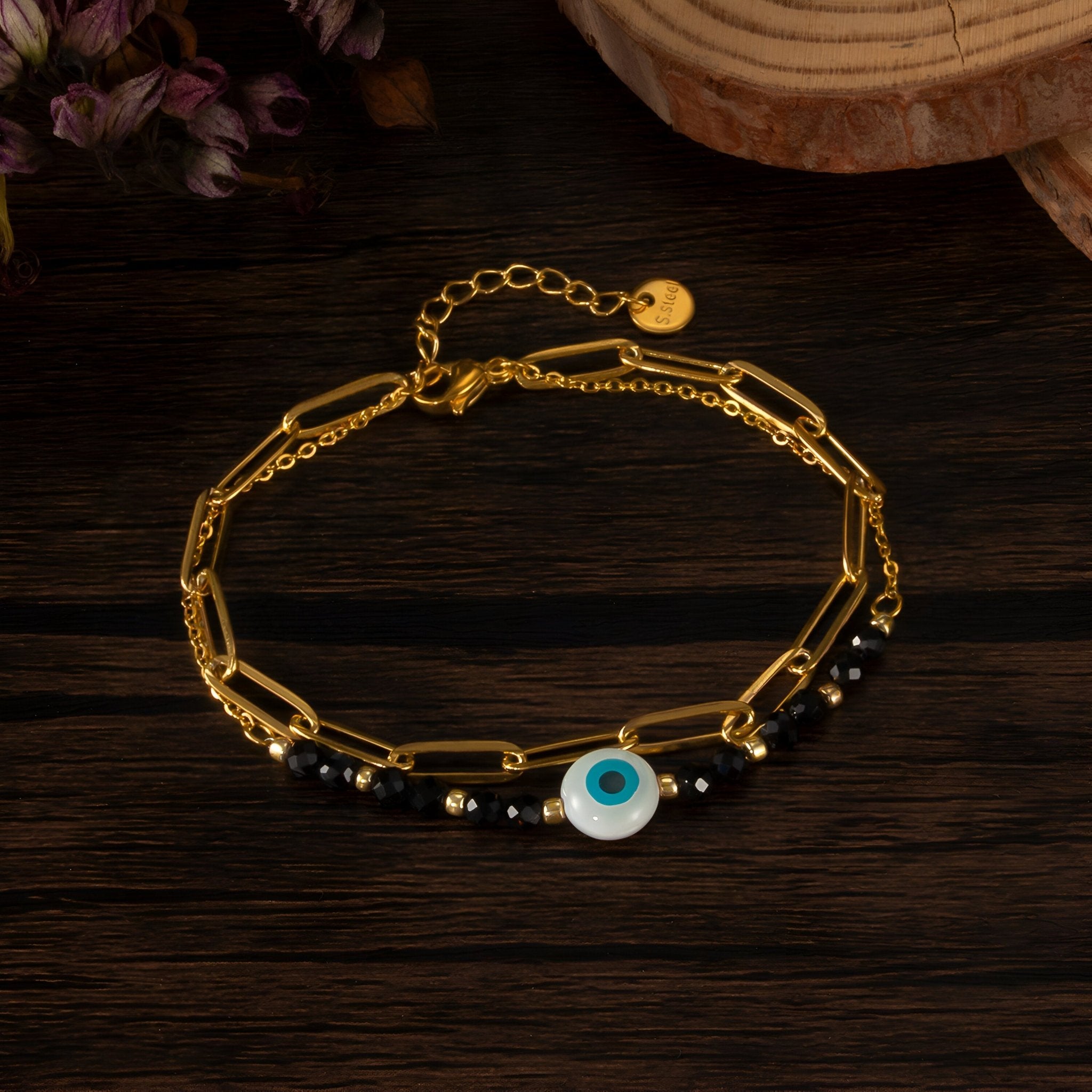 Bracelet or en acier inoxydable avec chaîne fine, perles noires et charm œil du diable bleu et blanc.