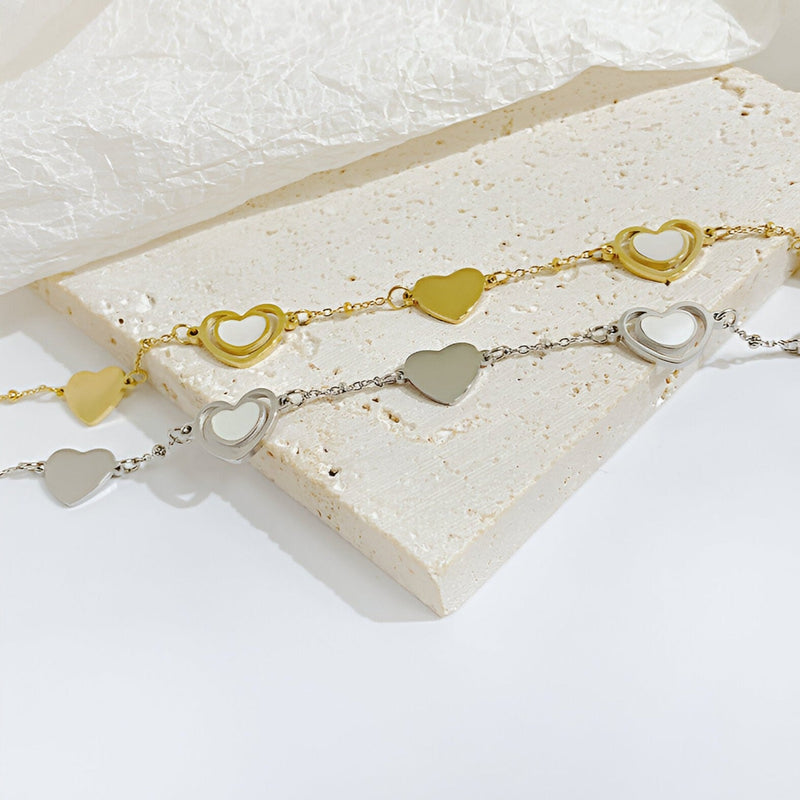 Bracelet femme en acier inoxydable avec cœurs ajourés alternés finition or et argent.