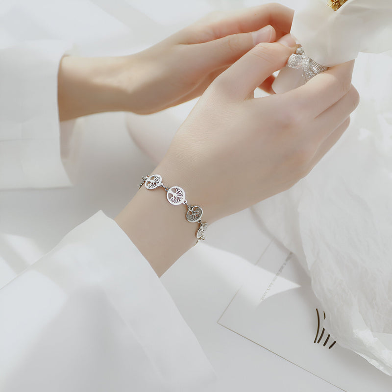 Bracelet femme en acier inoxydable argenté avec plusieurs pendentifs arbres de vie ronds et chaînette fine.