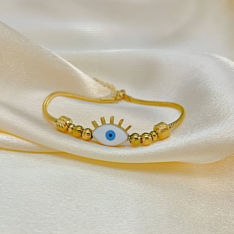 Bracelet en acier inoxydable doré avec pendentif œil bleu et perles dorées fines.