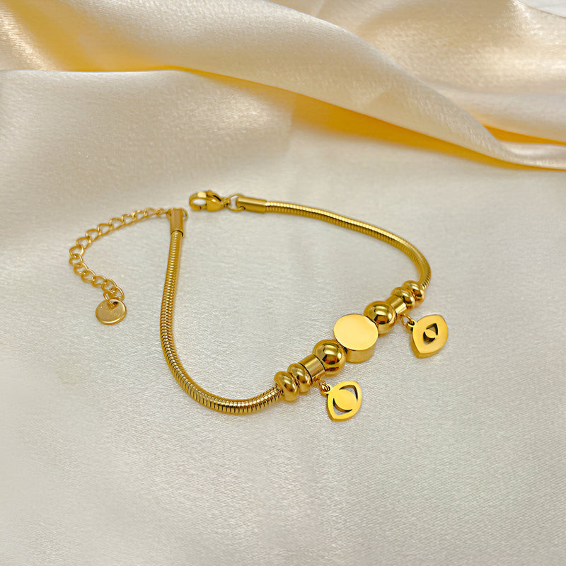 Bracelet femme en acier inoxydable doré avec pendentifs cœur et œil violet protection.