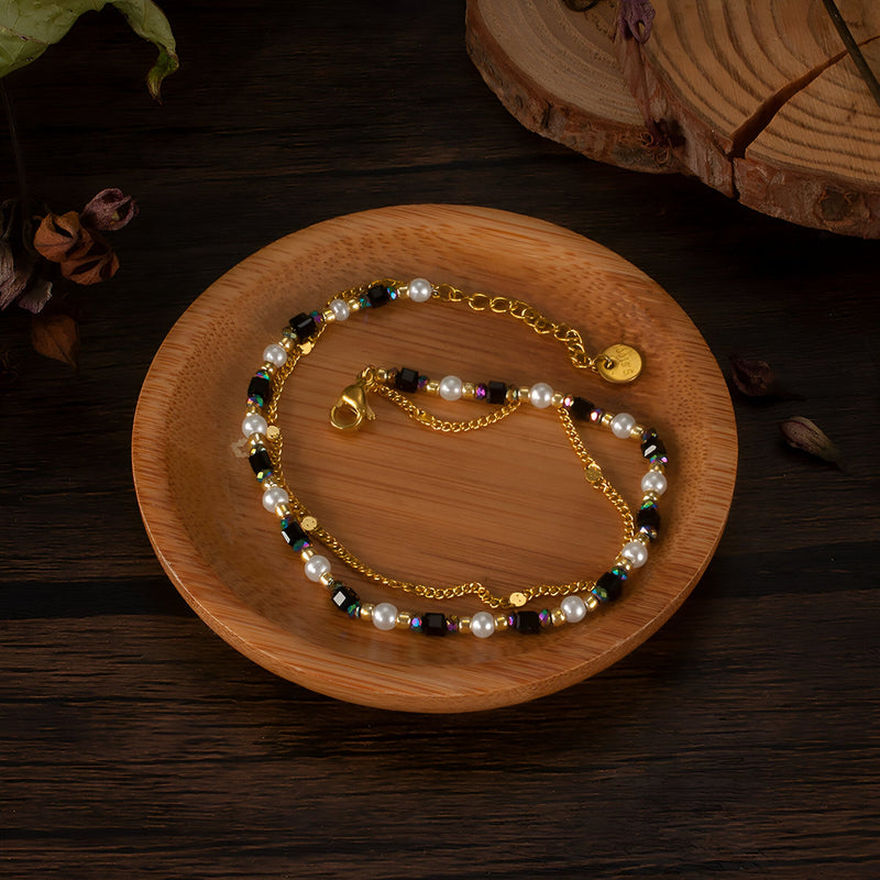 Bracelet femme en acier doré avec perles noires, blanches et pierres naturelles, chaîne fine réglable.