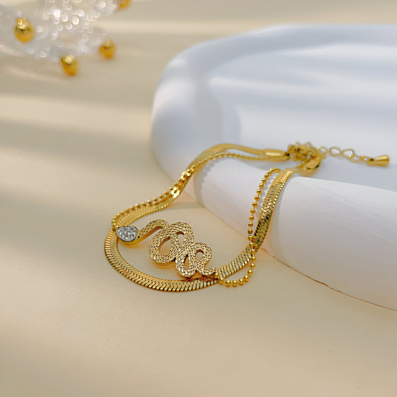 Bracelet serpent glissant en acier inoxydable doré avec détail tressé et fermoir réglable.