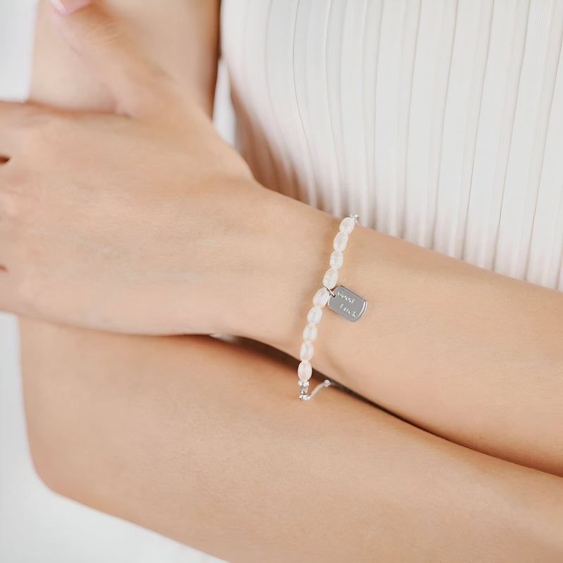 Bracelet femme en acier inoxydable avec perles blanches et breloque rectangulaire argentée.