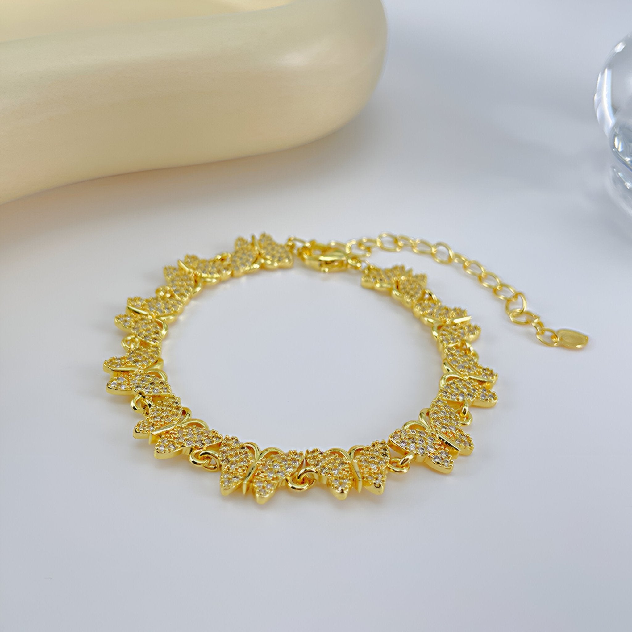 Bracelet femme en cuivre doré avec papillons ajourés sertis de zirconiums scintillants.
