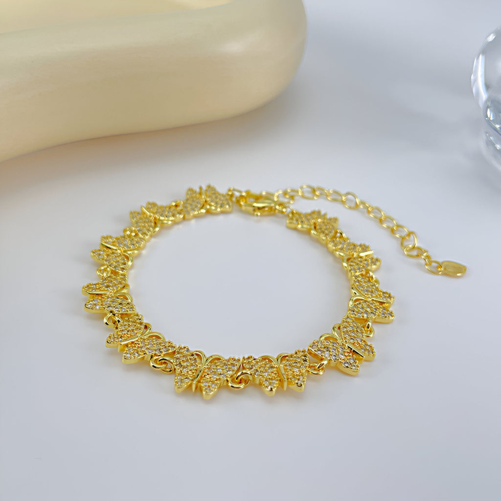 Bracelet femme en cuivre doré avec papillons ajourés sertis de zirconiums scintillants.