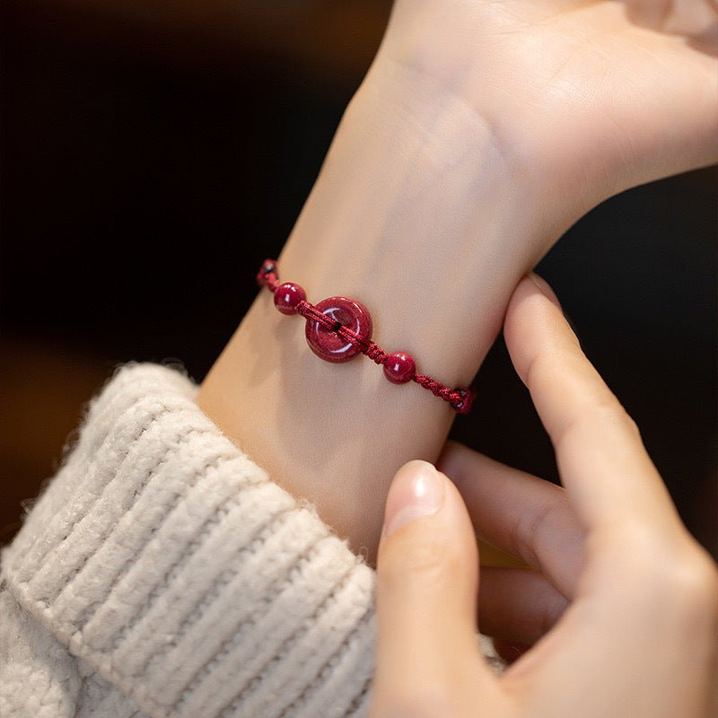 Bracelet rouge en fil de coton avec perles de cinabre, modèle Terya porté au poignet.