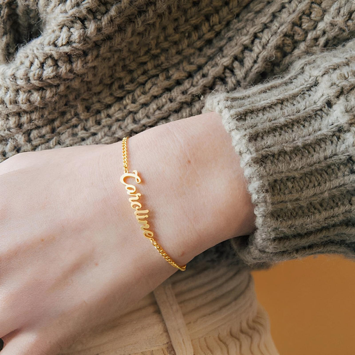 Bracelet ajustable en acier inoxydable doré avec prénom personnalisé en lettres cursives.