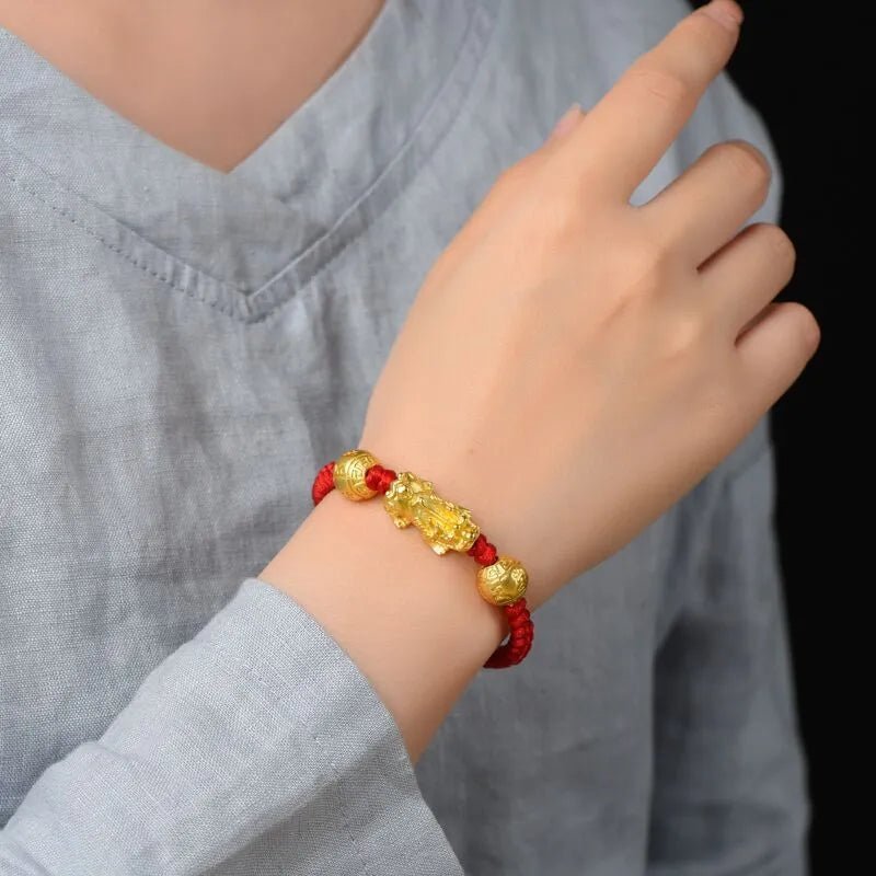 Bracelet rouge en fil ciré avec Pi Xiu doré porte-bonheur sur poignet, style tibétain.
