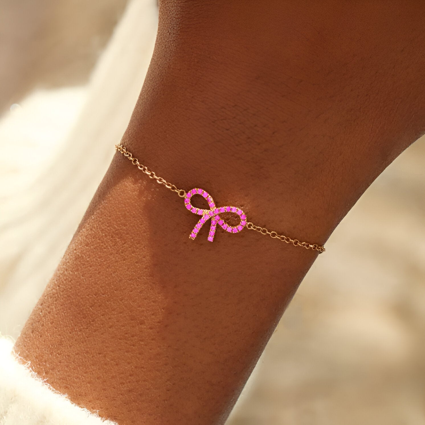 Bracelet en or rosé avec pendentif ruban rose lumineux délicat sur chaîne fine pour femme.