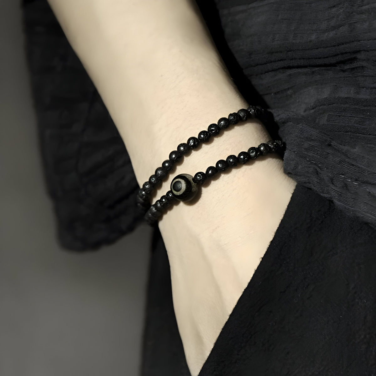 Bracelet double tour noir en pierres volcaniques avec perle de Dzi unique, style mixte élégant.