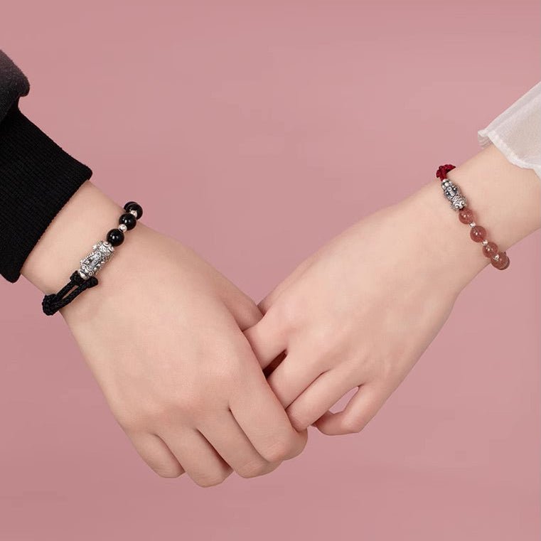Bracelet tibétain Pi Xiu en obsidienne noire avec breloque argentée sur fil rouge, porté en duo.