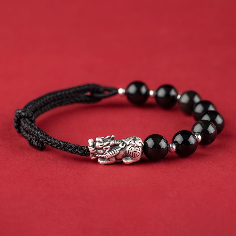 Bracelet tibétain Pi Xiu en pierres noires et fil tressé noir avec breloque en métal argenté.