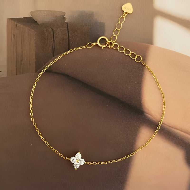 Bracelet fin en cuivre doré avec pendentif trèfle à 4 feuilles orné de petits cristaux blancs.