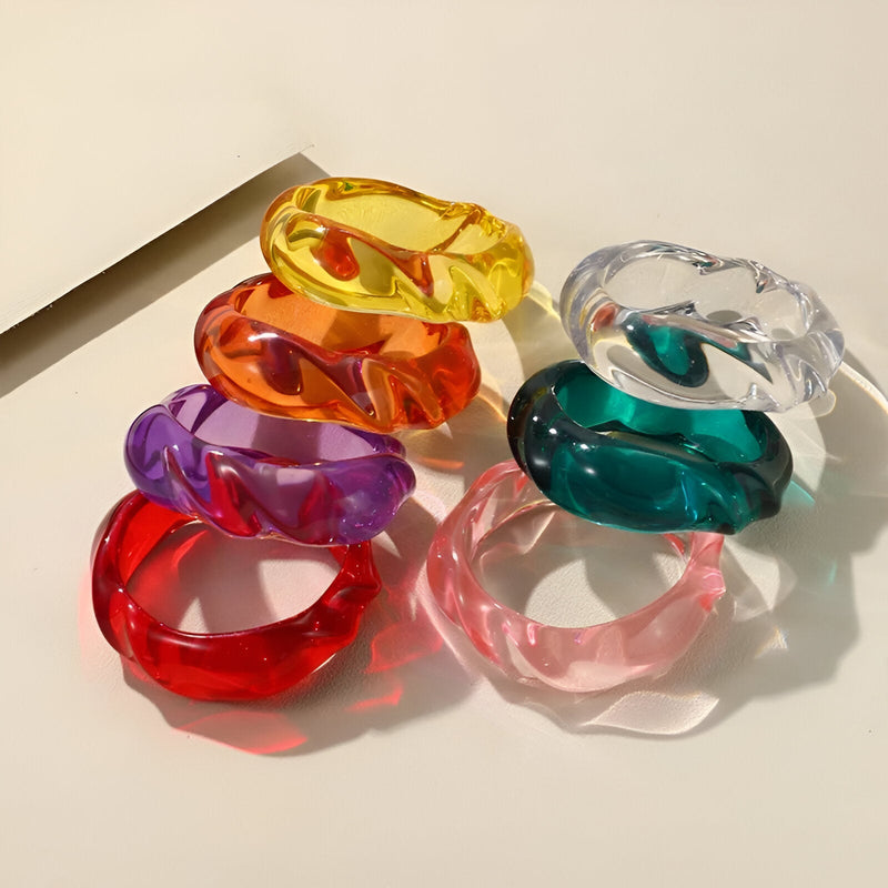 Bracelets en acrylique colorés translucides, forme ondulée, empilés sur fond clair.