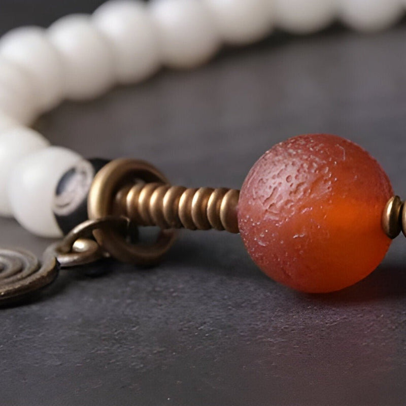 Bracelet perles blanches en graines de Bodhi avec perle orange en pierre d'agate texturée et détails bronze.