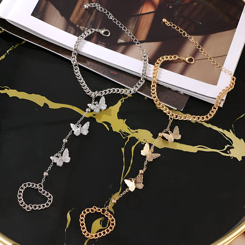 Bijou de main en acier inoxydable avec chaîne fine et trois papillons délicats, disponible en or et argent.
