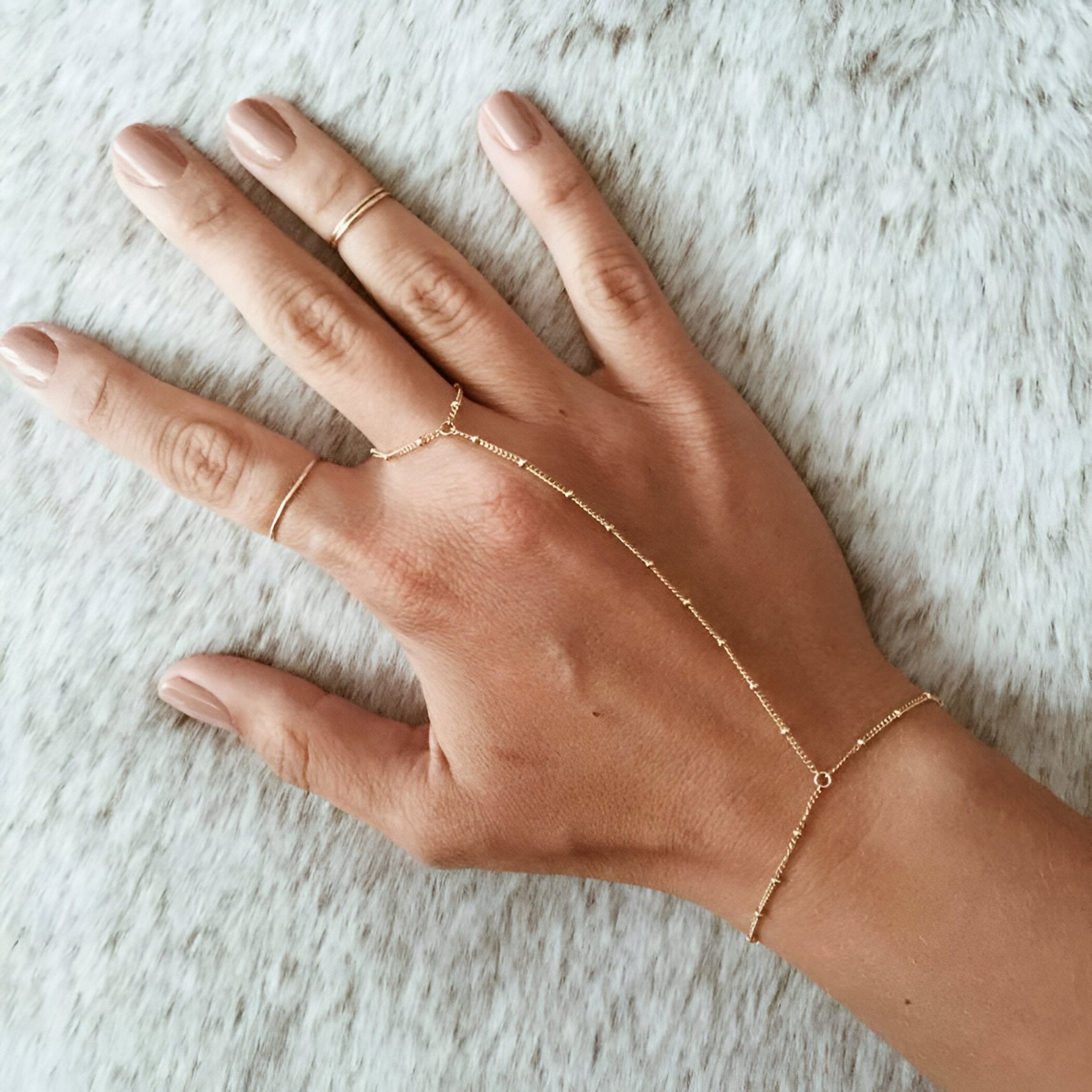 Bijou de main en acier inoxydable doré avec bracelet et anneaux reliés par une chaîne fine élégante.