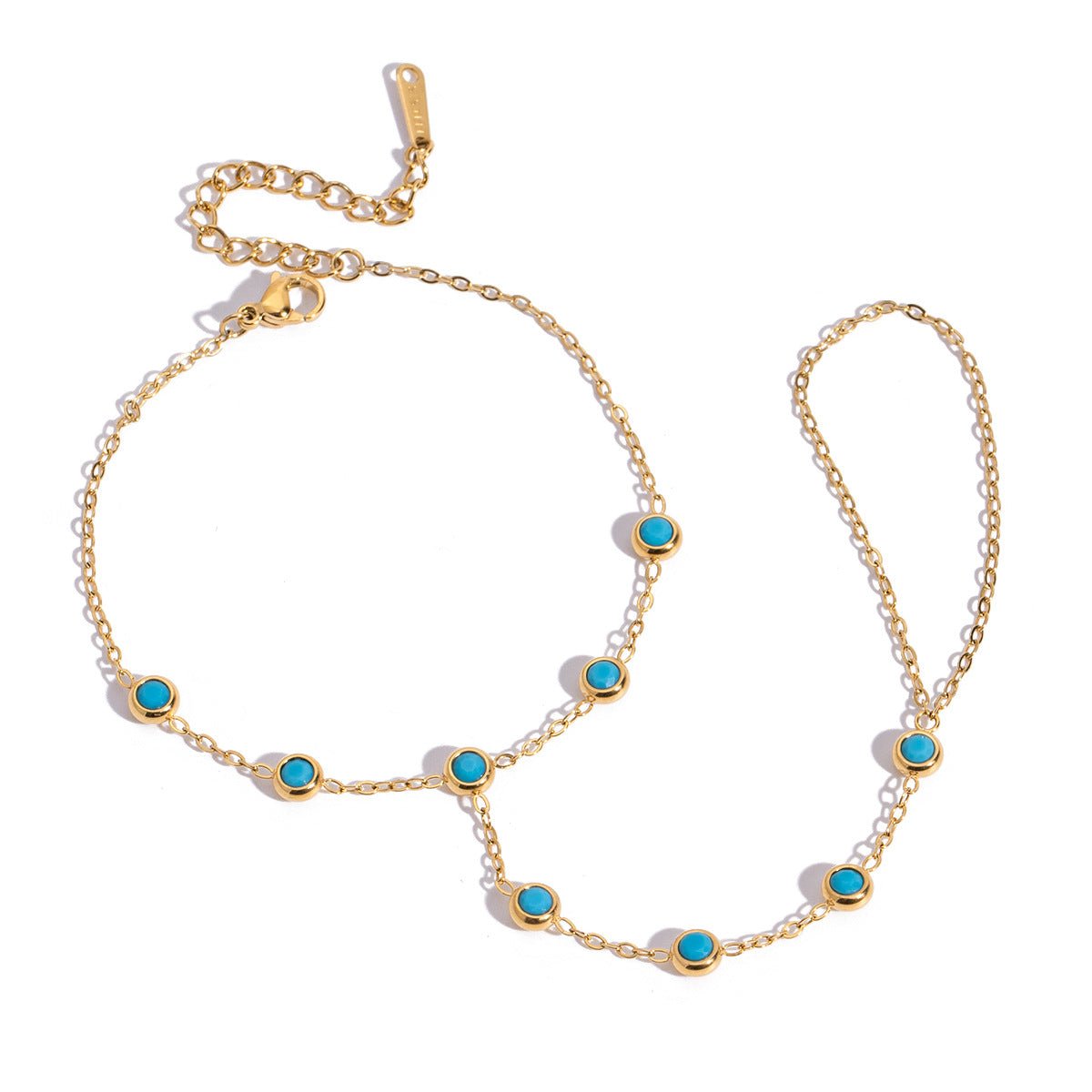 Chaînette de main dorée en acier inoxydable avec petites pierres turquoise ovales et maillons fins.