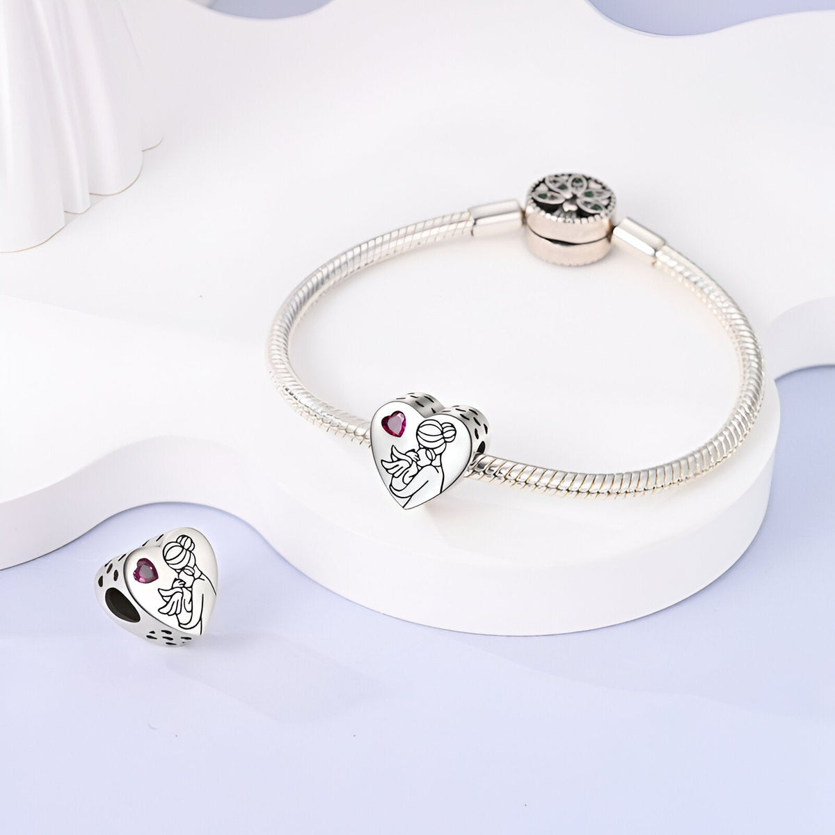 Bracelet argenté avec un charm cœur orné de gravure mère et enfant et pierre rose</s>.