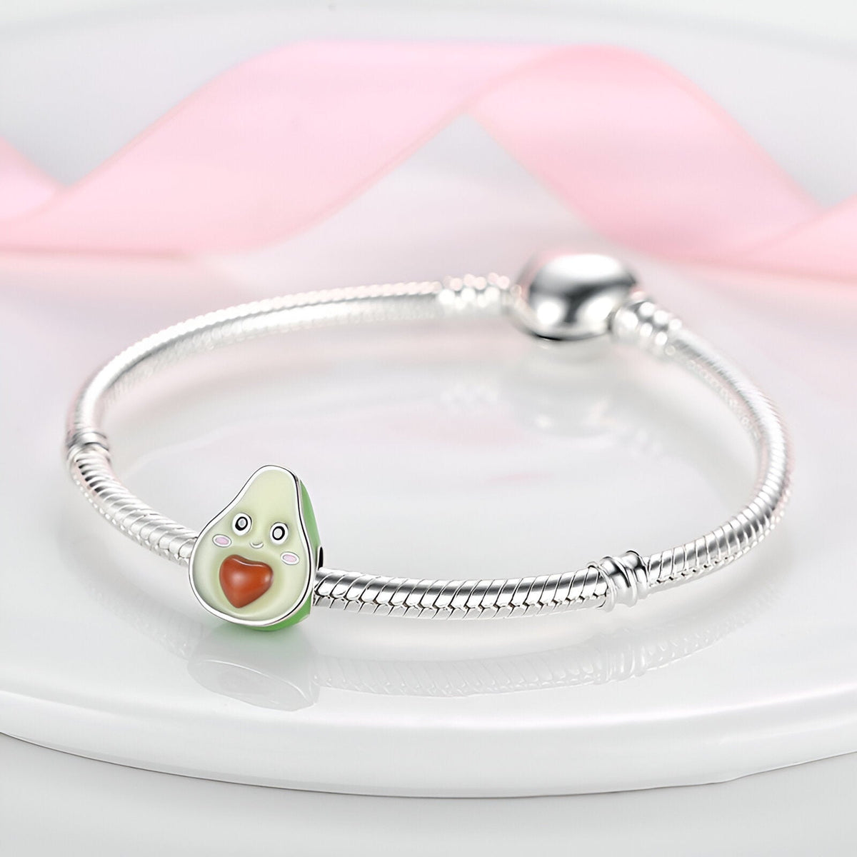 Bracelet argenté avec charm avocat vert clair et noyau en forme de cœur rougeî.