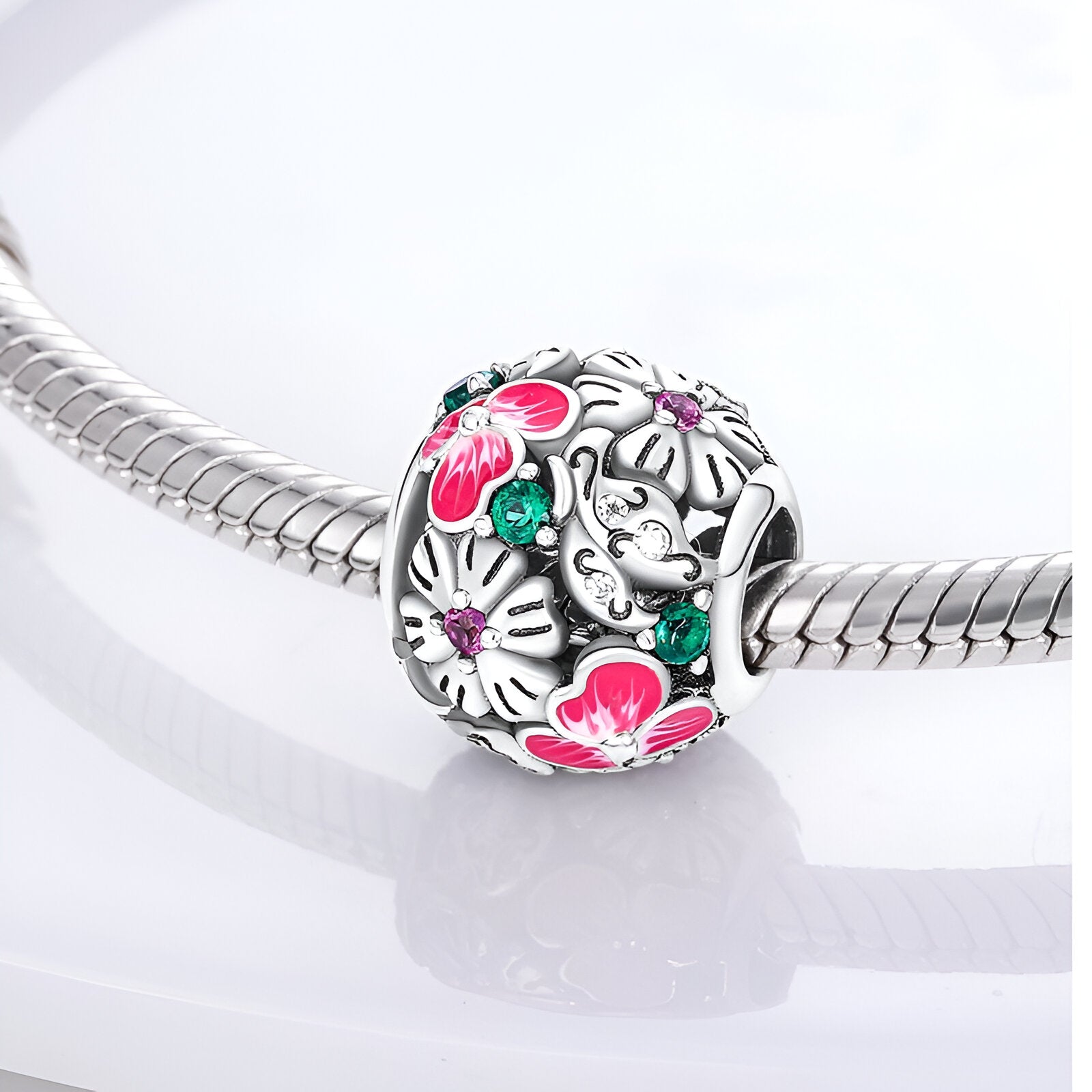 Charm rond en argent avec fleurs roses et blanches émaillées, détail feuillage vert, modèle Athalie.
