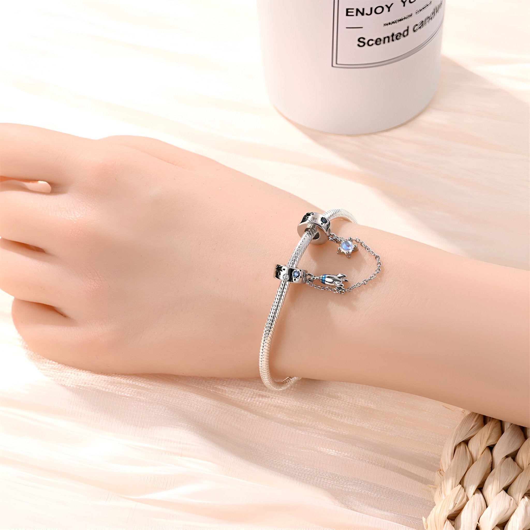 Bracelet fin argenté avec chaînette, pendentifs fusée spatiale et étoile, style délicat.