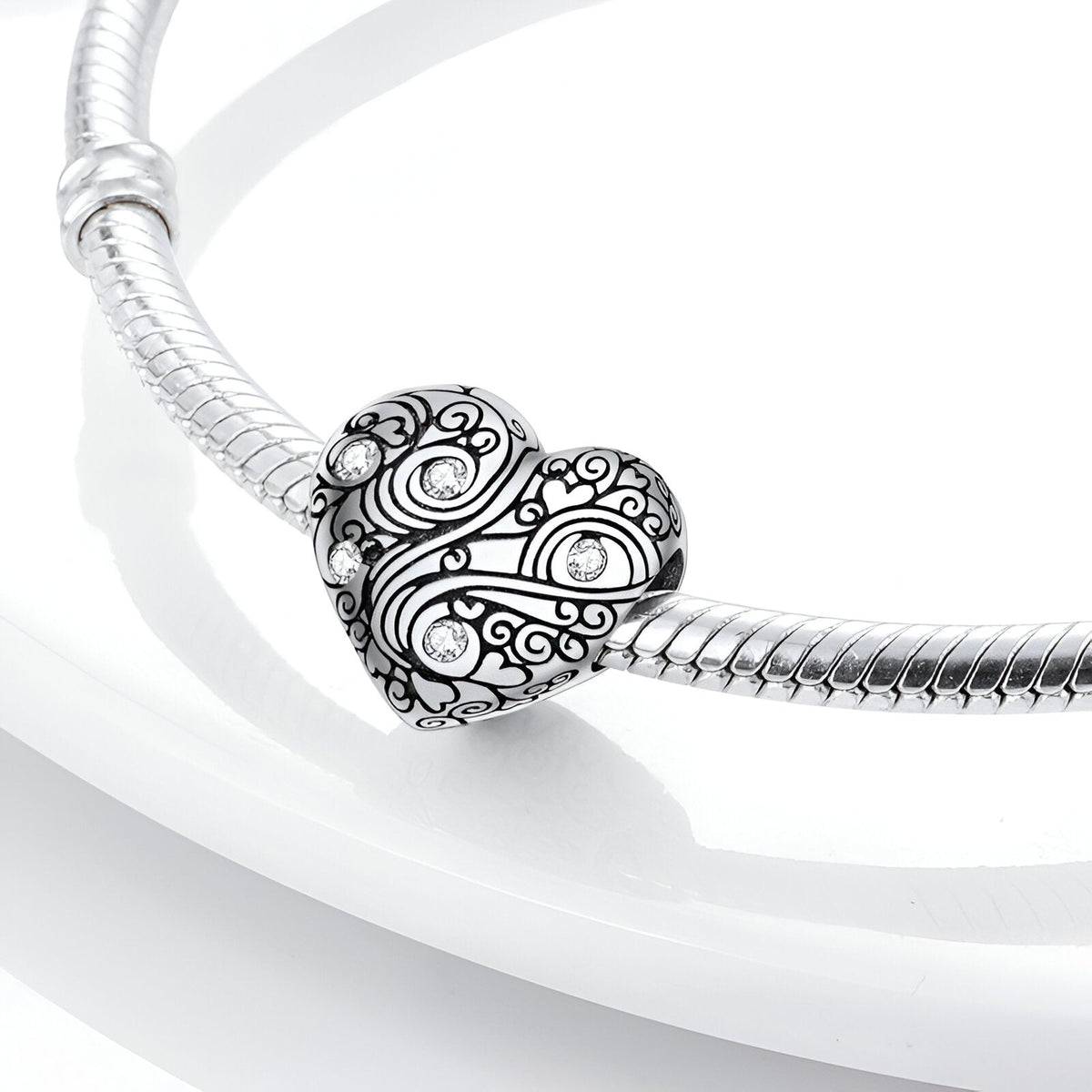 Bracelet serpent argent avec charm cœur Leontine gravé de motifs floraux et arabesques.