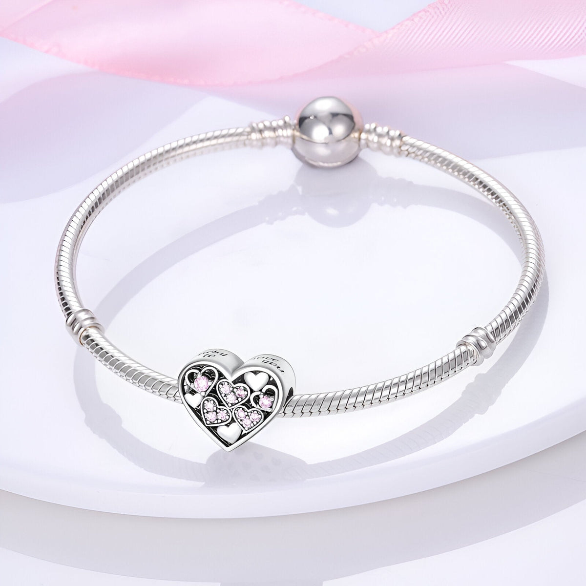 Bracelet argent avec charm coeur incrusté de petits coeurs roses scintillants.