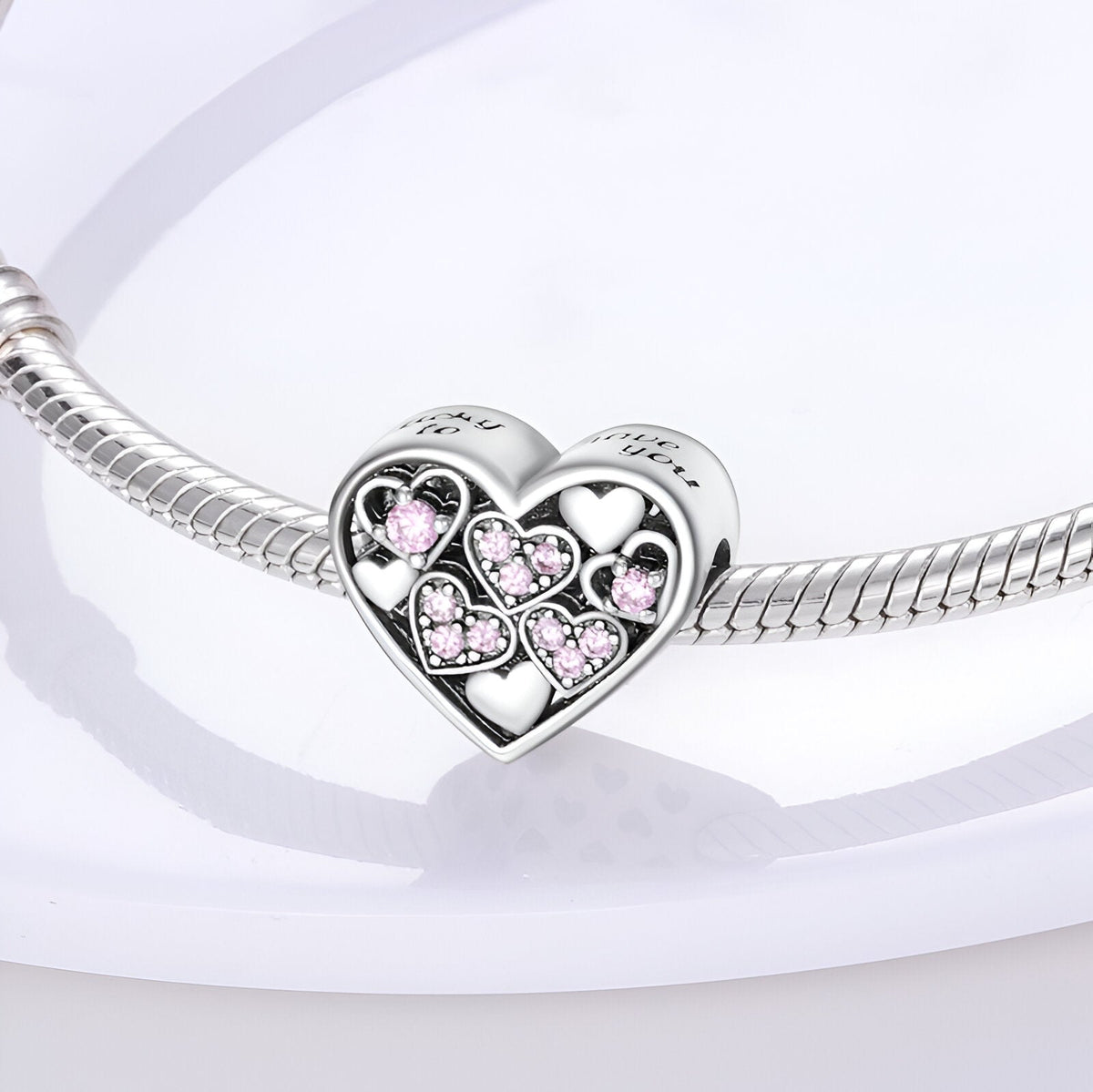 Charm cœur en argent avec petits cœurs roses incrustés, monté sur un bracelet serpent argenté.