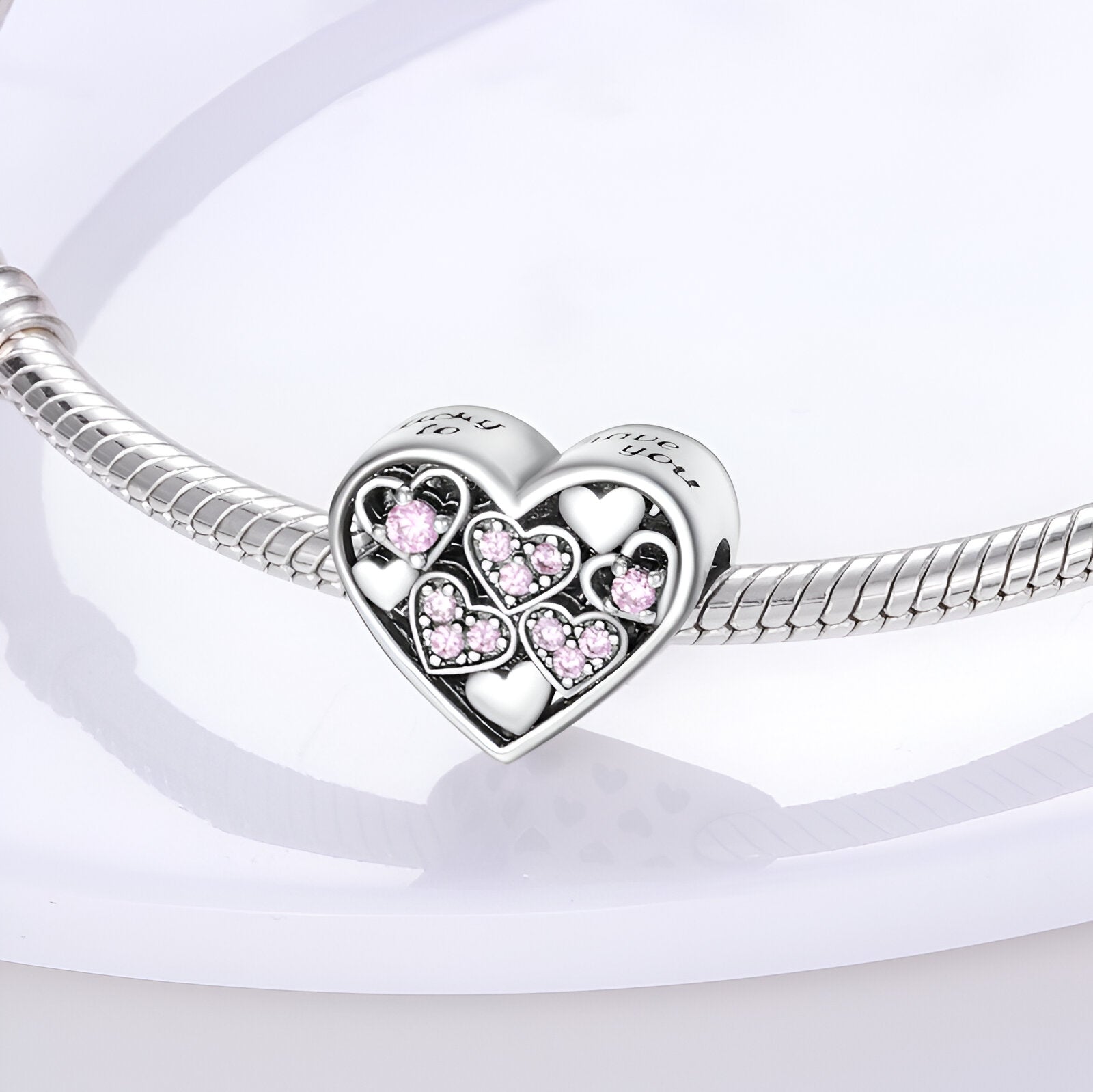 Charm cœur en argent avec petits cœurs roses incrustés, monté sur un bracelet serpent argenté.