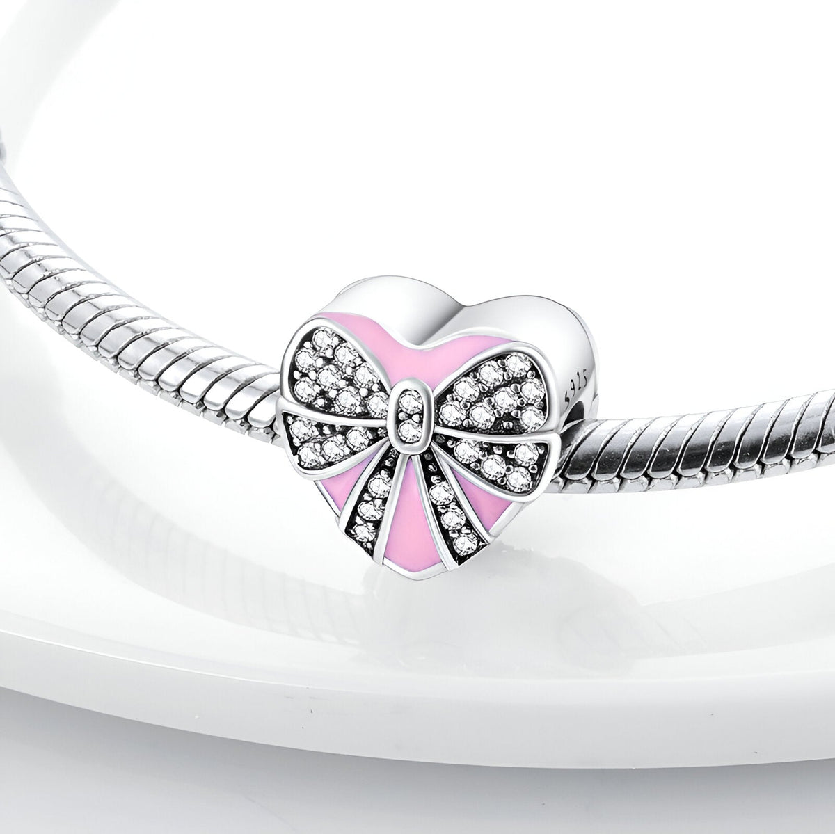 Charm en forme de cœur argenté avec ruban rose et strass, monté sur bracelet serpent argenté.