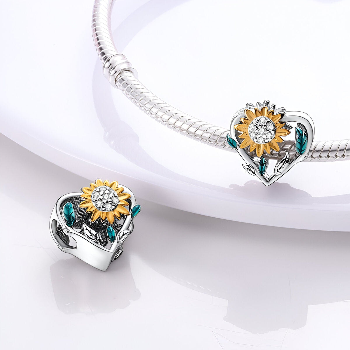 Charm en forme de cœur argenté orné d'un tournesol jaune et de feuilles vertes sur bracelet serpent.