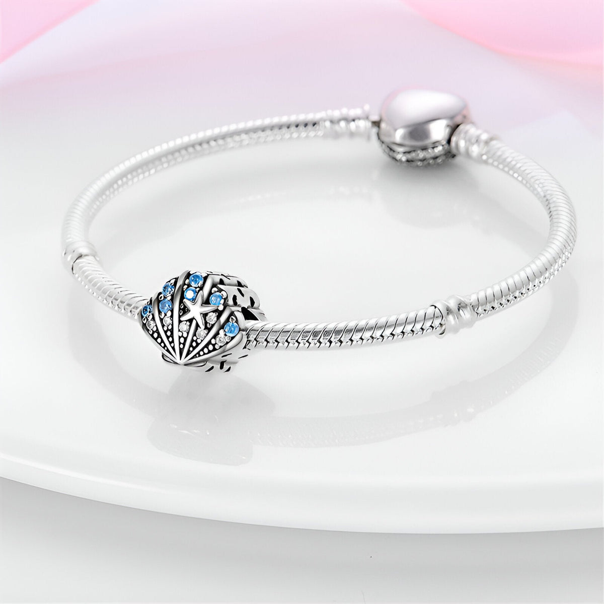 Bracelet argenté avec charm coquillage ajouré orné de perles et étoiles bleues.