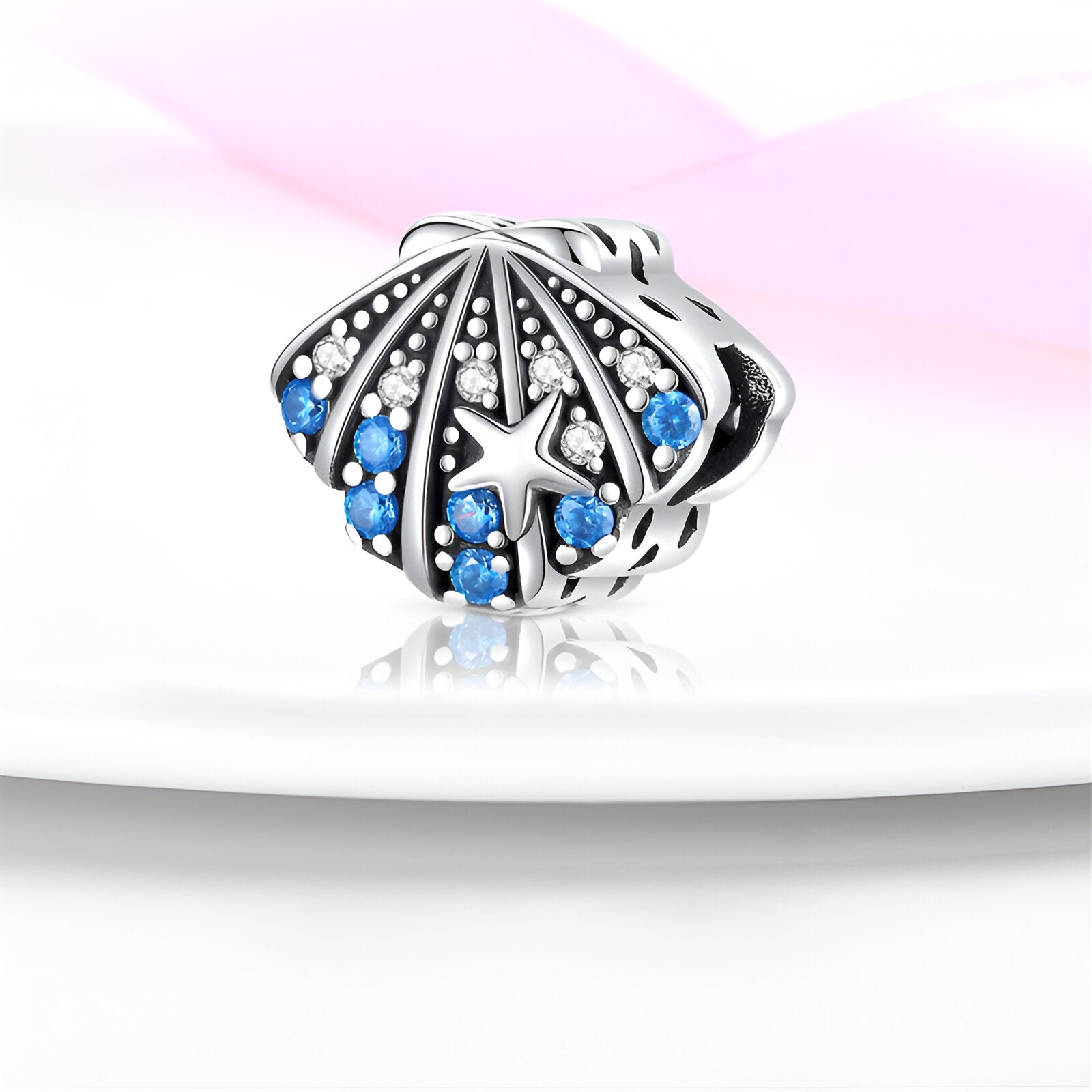 Charm coquillage en argent orné de petites perles blanches et strass bleu ciel.